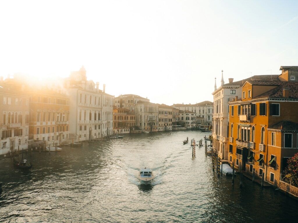 Boat on canal with buildings at sunrise