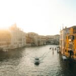 Boat on canal with buildings at sunrise
